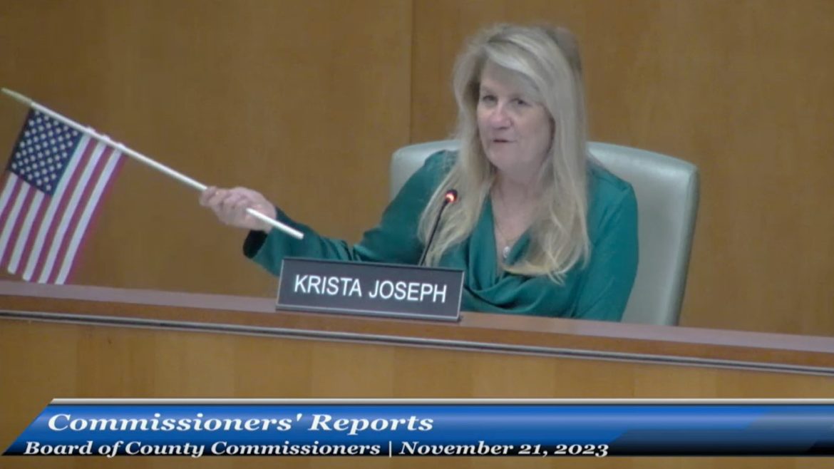 St. Johns County Commissioner Krista Joseph waves an American flag as she begins her comments during a meeting Nov. 21, 2023. 