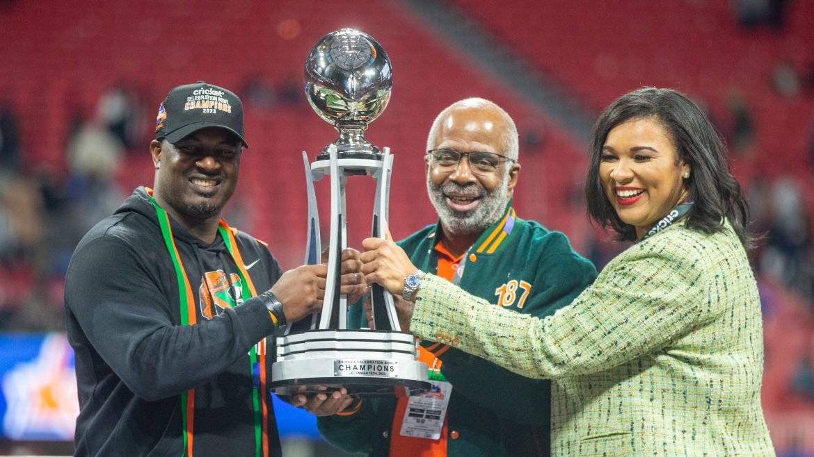 O técnico de futebol americano da Florida A&M, Willie Simmons, o presidente da universidade Dr. Larry Robinson e a diretora atlética Tiffani Sykes levantam o troféu Celebration Bowl. A FAMU (12-1) encerrou sua melhor temporada em 45 anos com uma vitória no Celebration Bowl de 2023. A FAMU venceu Howard por 30-26 no sábado, 16 de dezembro de 2023 no Estádio Mercedes-Benz em Atlanta, Geórgia. | Will Brown, Jacksonville Today