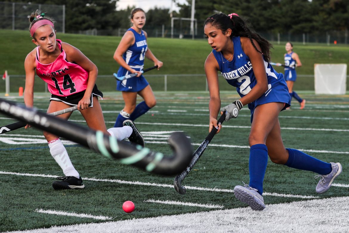 Shivya Desai, de Warren Hills, trabalha a bola ao longo da linha lateral contra Mia Beneducci (14), de North Hunterdon, em 5 de outubro de 2023.