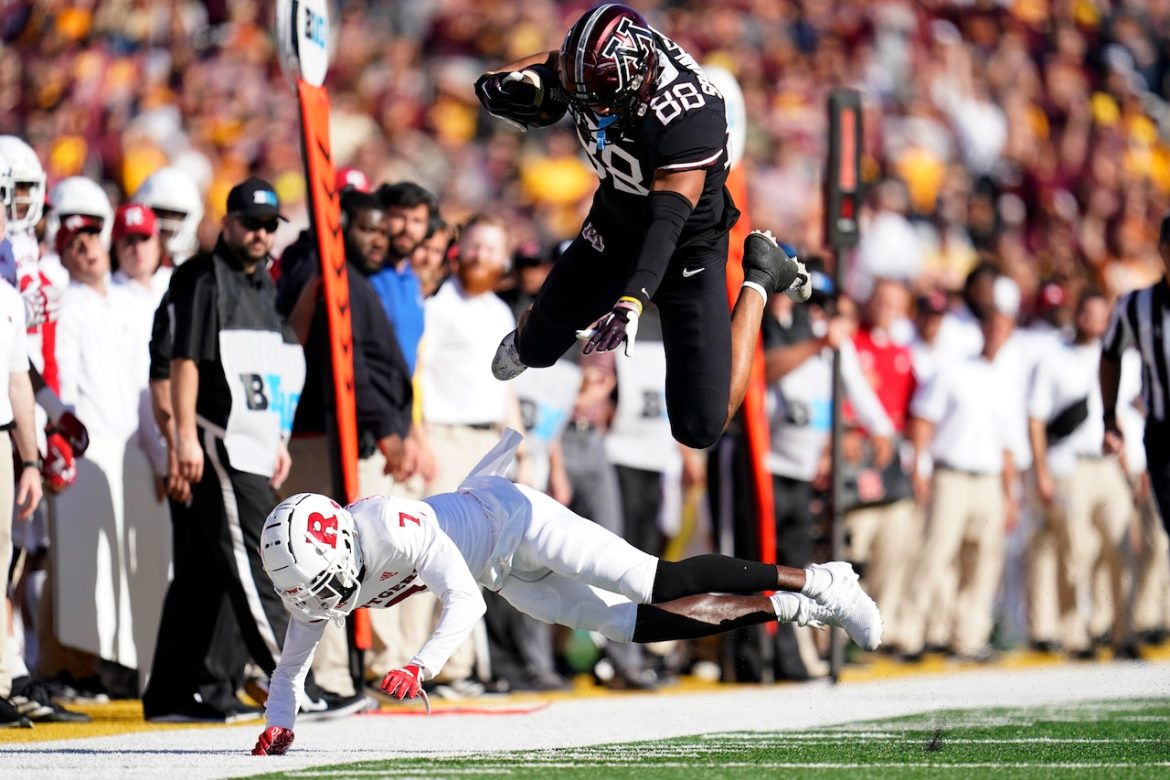 O tight end de Minnesota, Brevyn Spann-Ford (88), é abordado pelo zagueiro de Rutgers, Robert Longerbeam (7), durante a primeira metade de um jogo de futebol americano universitário da NCAA, sábado, 29 de outubro de 2022, em Minneapolis.