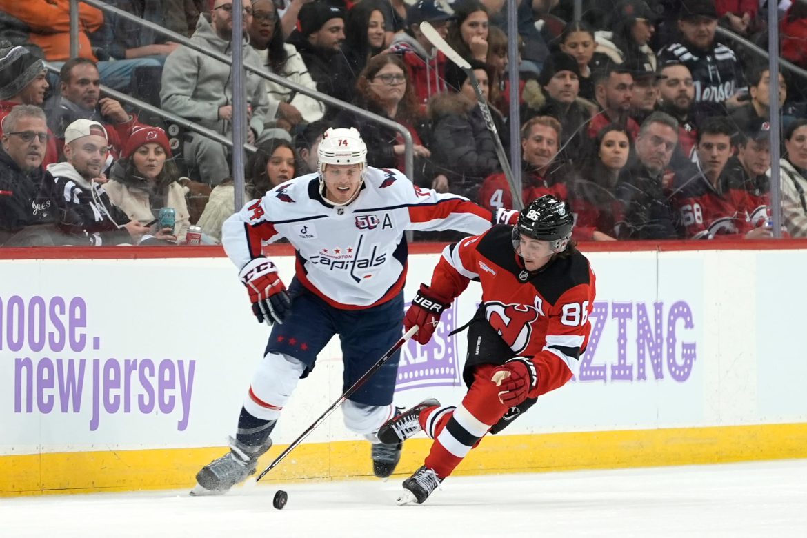 Jack Hughes, do New Jersey Devils, à direita, patina com o disco contra John Carlson, do Washington Capitals, à esquerda, durante o primeiro período de um jogo de hóquei da NHL no sábado, 30 de novembro de 2024, em Newark, NJ (AP Photo/Pamela Smith)