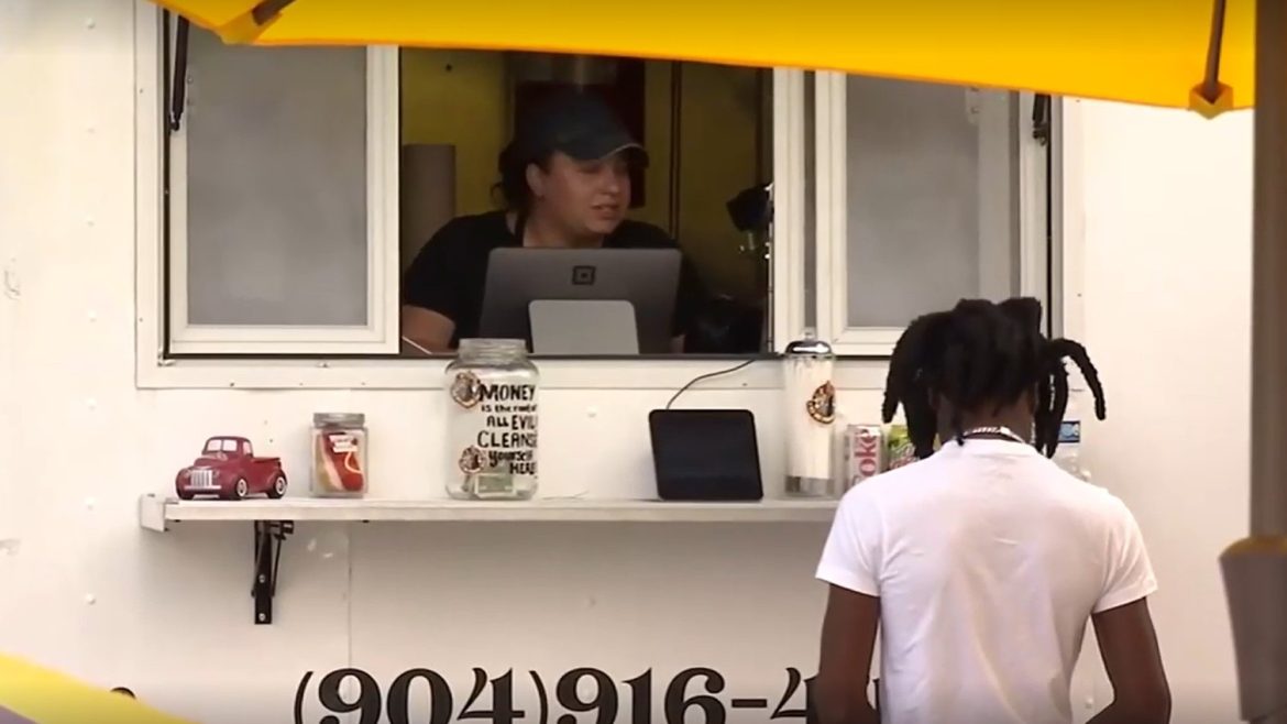 A young person gets service at a food truck window.